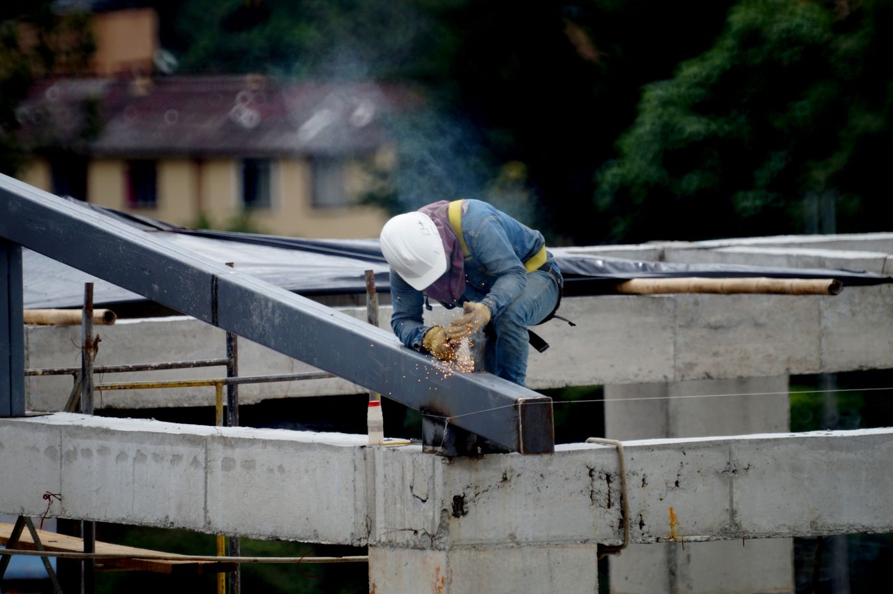 about-01 A construction worker welding steel beams on a building framework outdoors, ensuring structural safety.